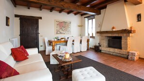 Ein Wohnzimmer mit Kamin, weißen Möbeln und einem Essbereich mit Stühlen und Tisch.