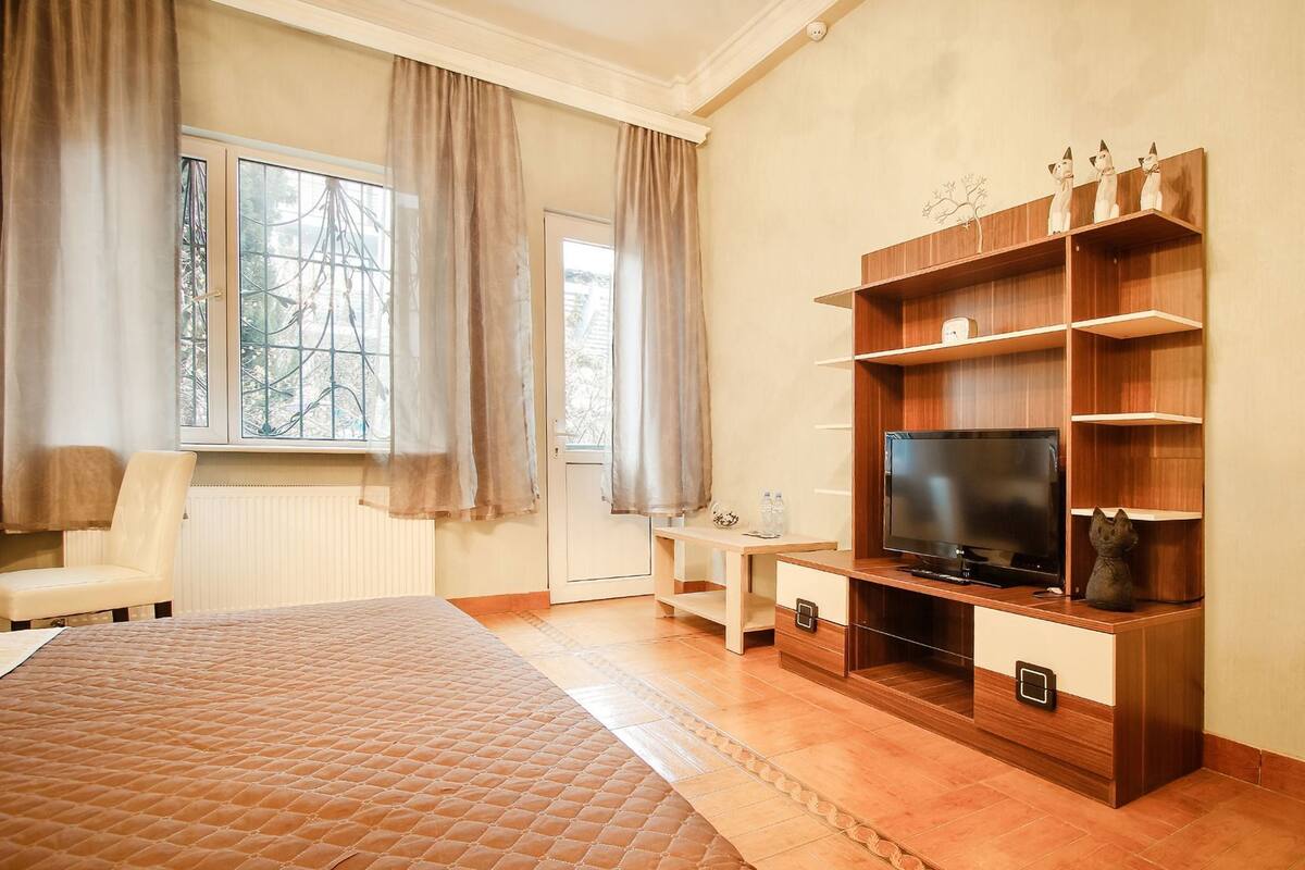 Ett sovrum med en säng, en tv, ett skrivbord och en stol.