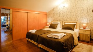 A double bed with two pillows, a nightstand, a wooden wardrobe, and a patterned wallpaper. - Hotel Toma's House (Tbilisi)