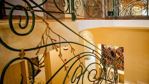 A staircase with ornate metal railings and a colorful abstract painting on the wall. - Hotel Toma's House (Tbilisi)