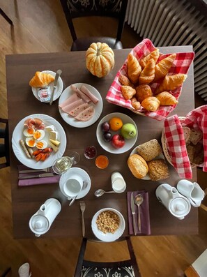 A breakfast table with croissants, ham, eggs, sausages, and various fruits and bread. - Rothenfels Panorama Hotel (Immenstadt im Allgaeu)