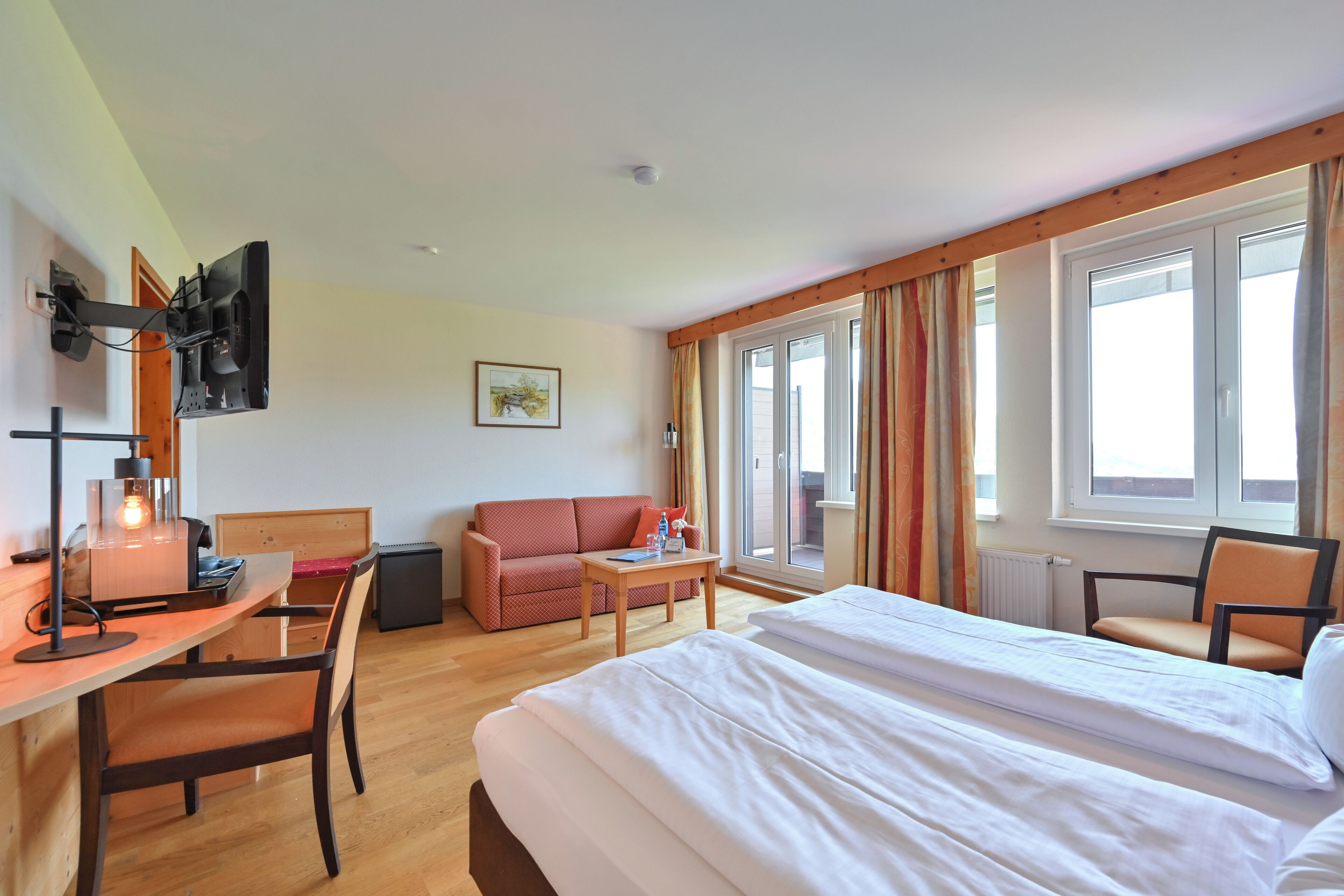 A hotel room with a bed, desk, chair, and a small table.