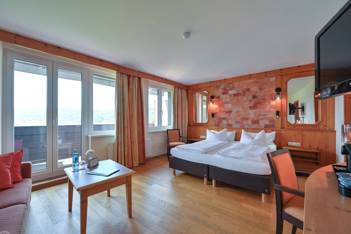 A hotel room with a large bed, a desk, a chair, and a TV.