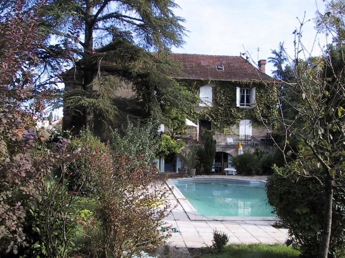 Ein Haus mit Swimmingpool, umgeben von Bäumen und Sträuchern.