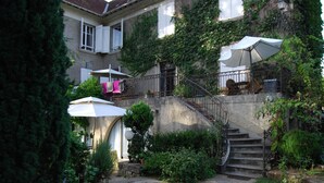 Una escalera de piedra que lleva a un balcón con mobiliario exterior y sombrillas.
