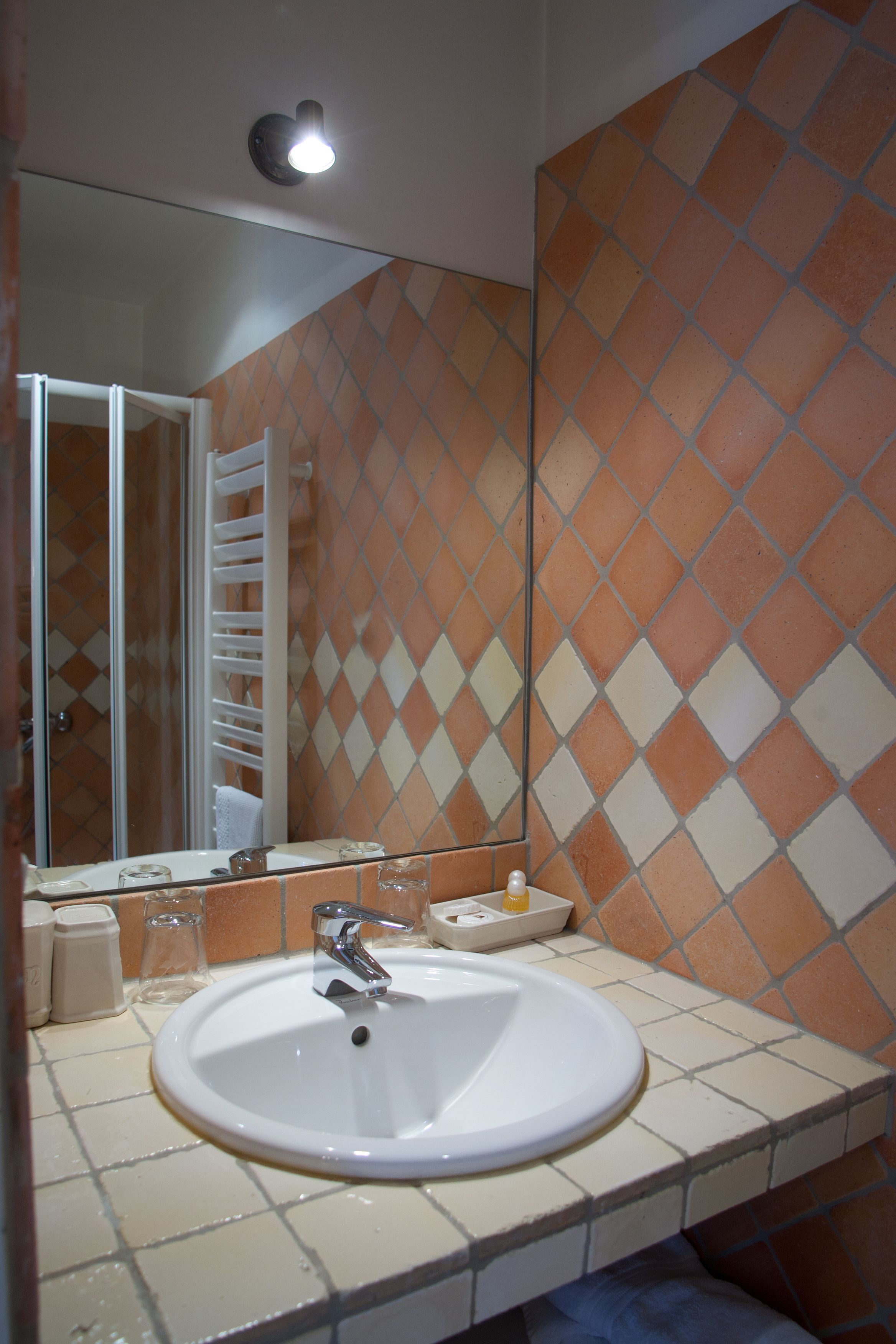 Un baño con un lavamanos blanco, un espejo y una pared de azulejos con un diseño de rombos.