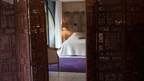 Una habitación tradicional con una cama, una silla y un mosquitero de madera.