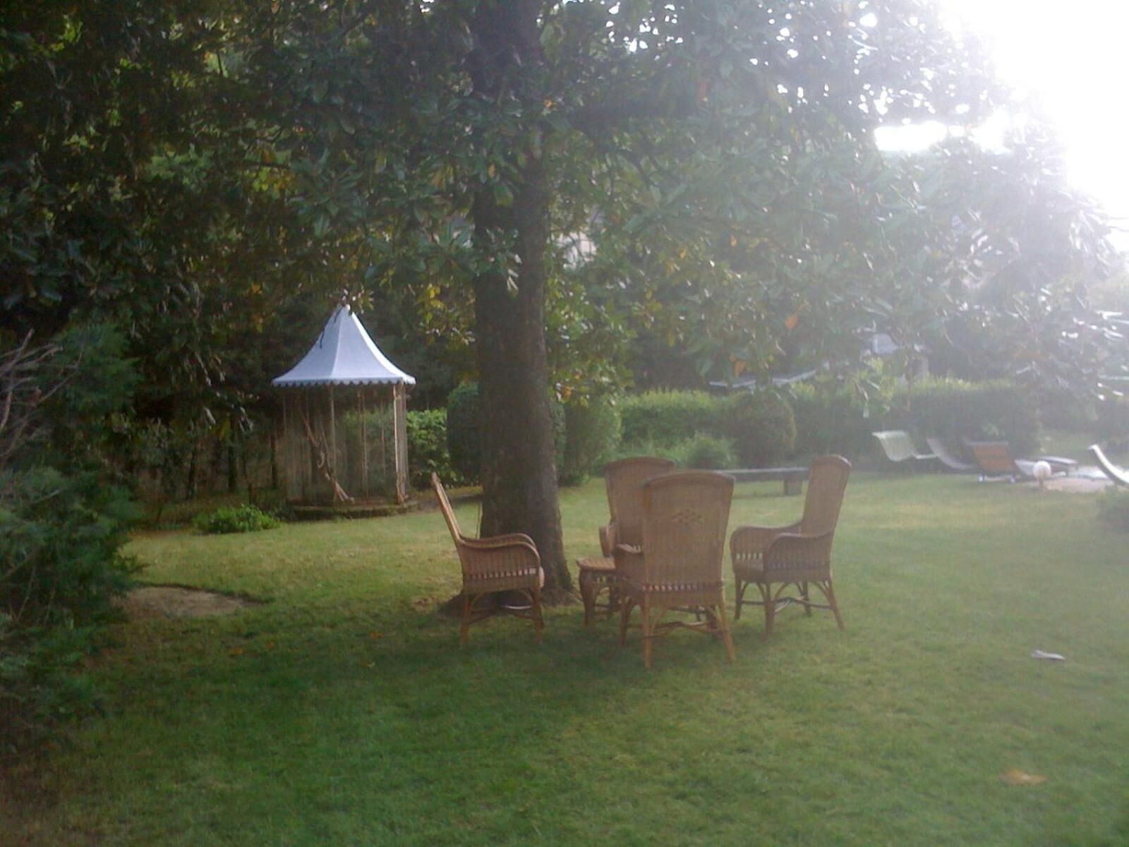 Een prieeltje, rieten stoelen en een gazon.