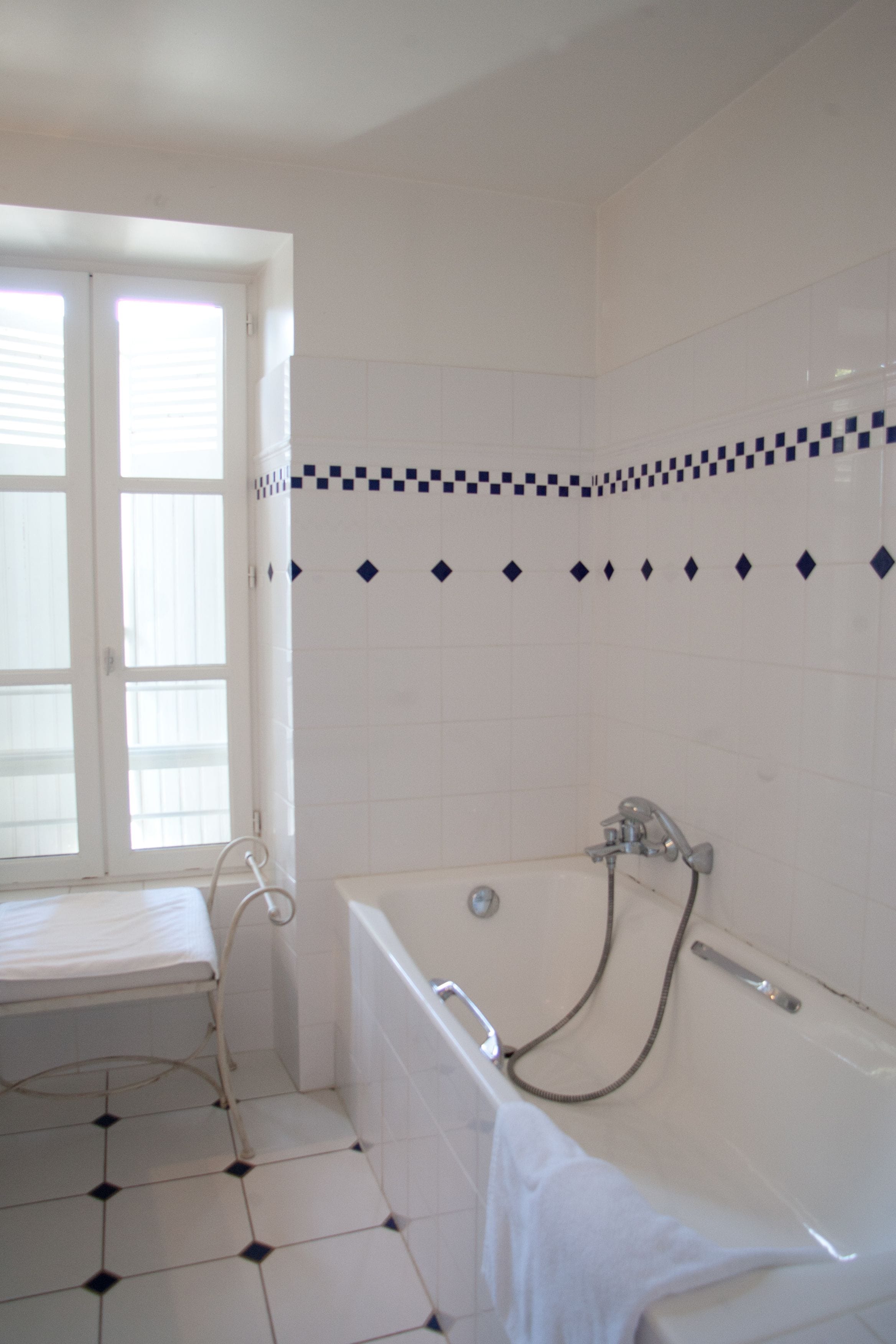 Un baño con bañera, ventana y suelo de baldosas.