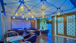 Un restaurante moderno con suelo de madera, iluminación azul y una pared verde con una estatua de Buda.
