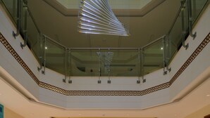 Un vestíbulo amplio con suelo de mármol, un diseño decorativo en el centro y una barandilla de cristal que da al nivel inferior.