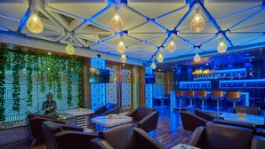 Zona de bar moderna con asientos de cuero, una estatua de Buda y una barra con botellas.