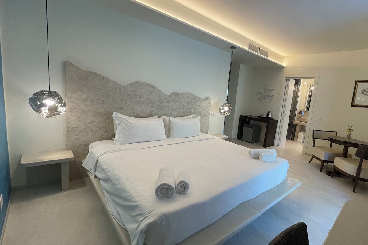 A modern hotel room with a large bed, bedside tables, a desk, and a chair.