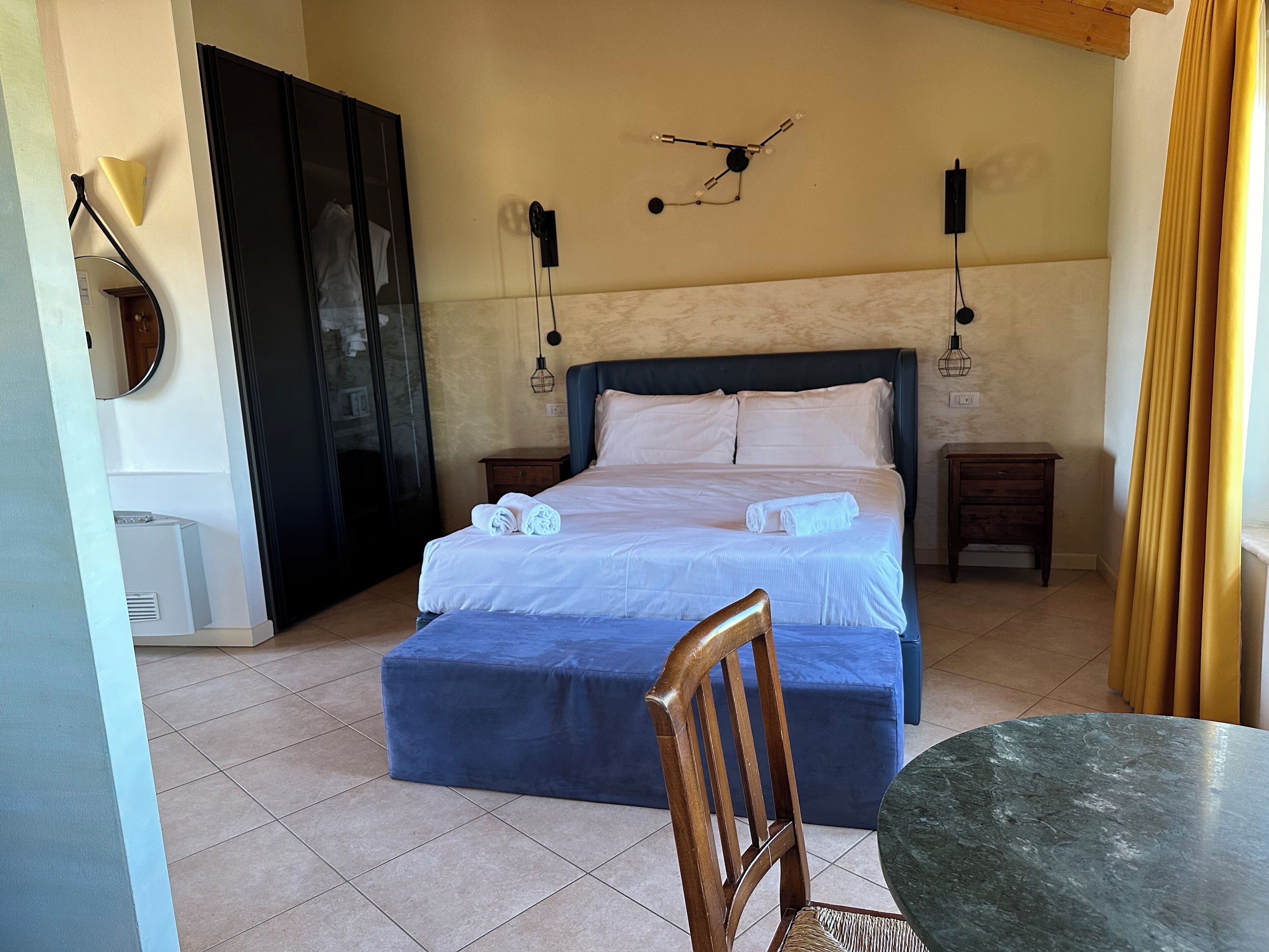 Ein Schlafzimmer mit einem Bett, Nachttischen, einem Sessel, einem Tisch und einer Wanduhr.