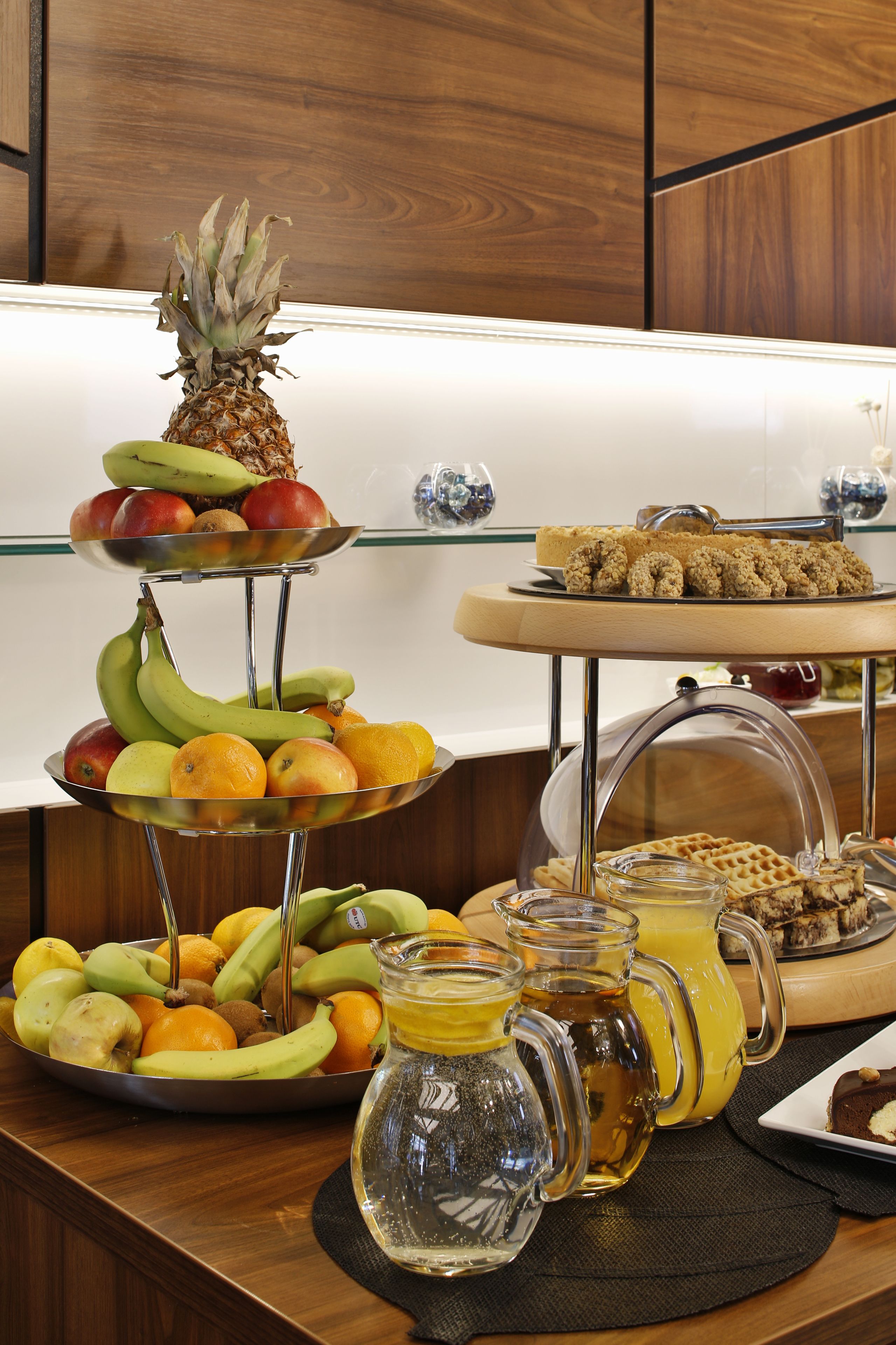 Een buffet met verschillende soorten fruit, gebak en drankjes.