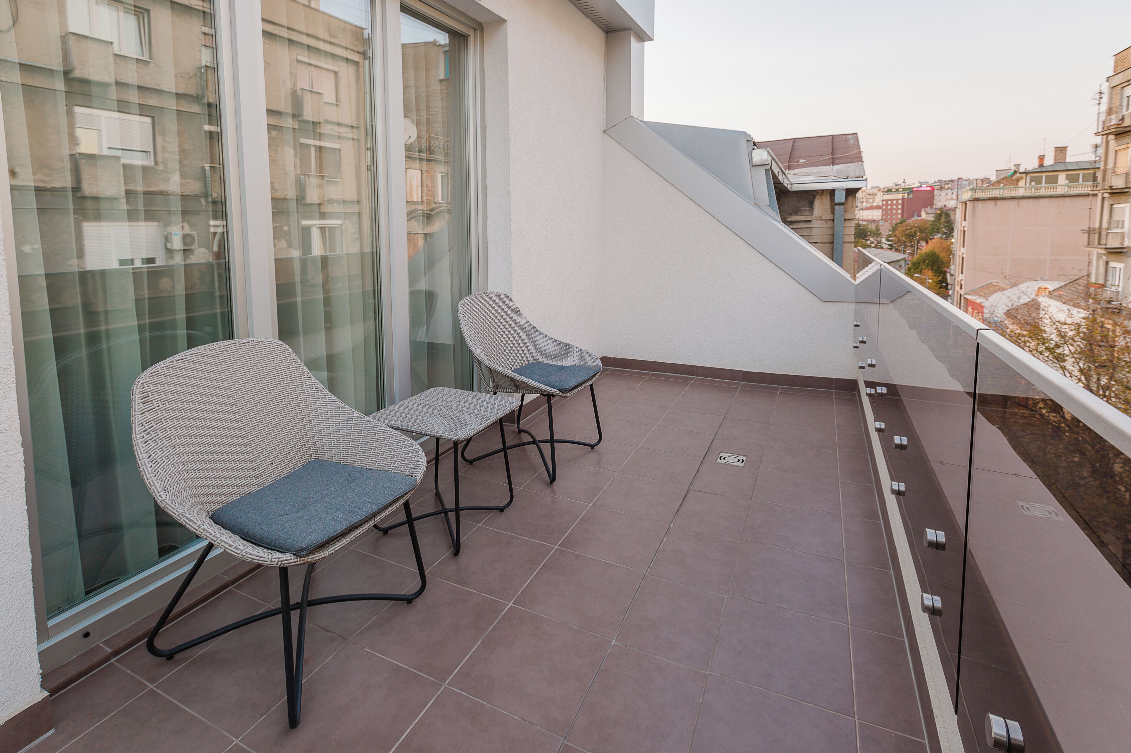 Un balcone con due poltrone in vimini e un tavolino, con vista sulla città.