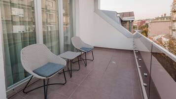Un balcone con due poltrone in vimini e un tavolino, con vista sulla città.