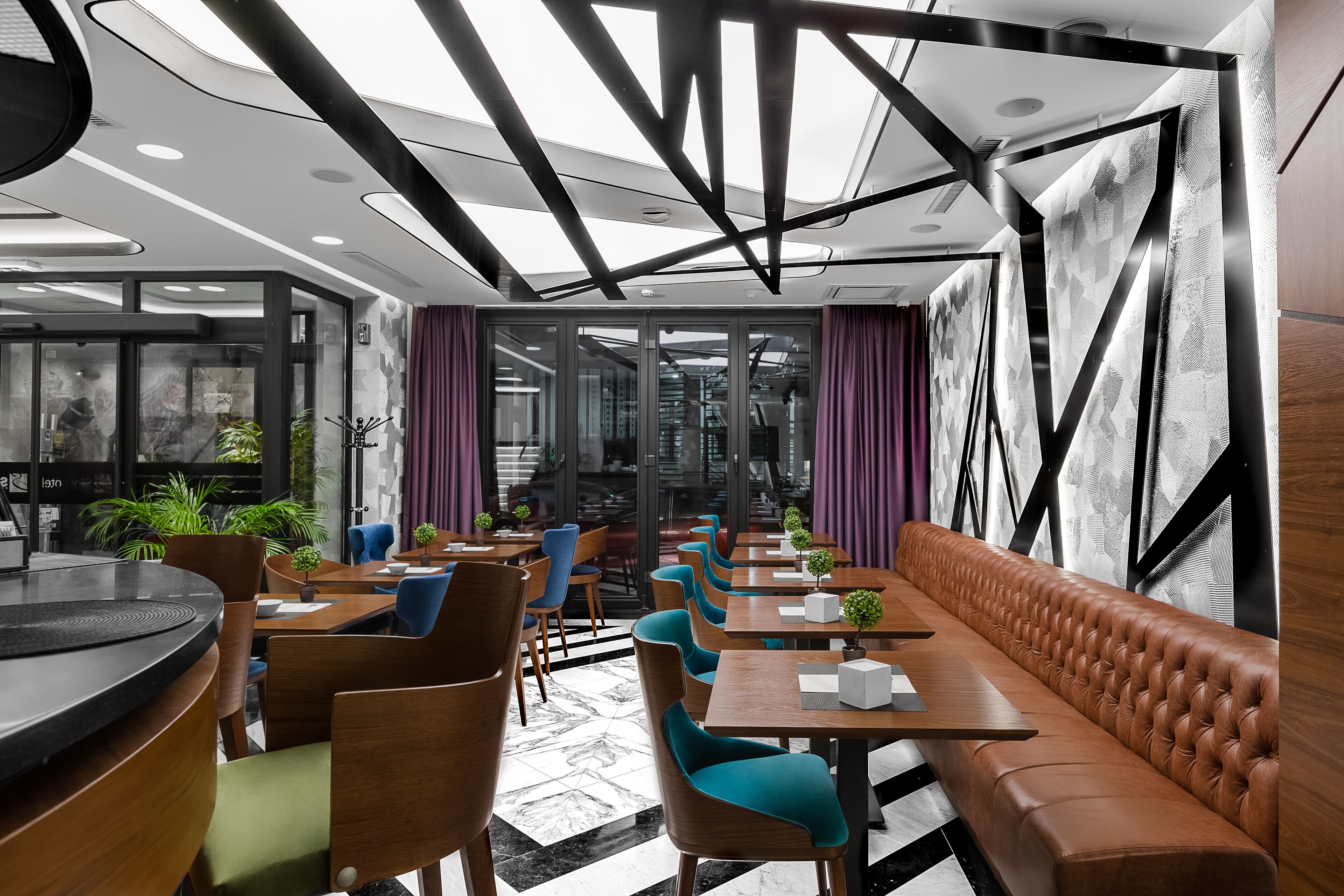 Et moderne restaurantinteriør med en lang træbænk, flere borde og stole.