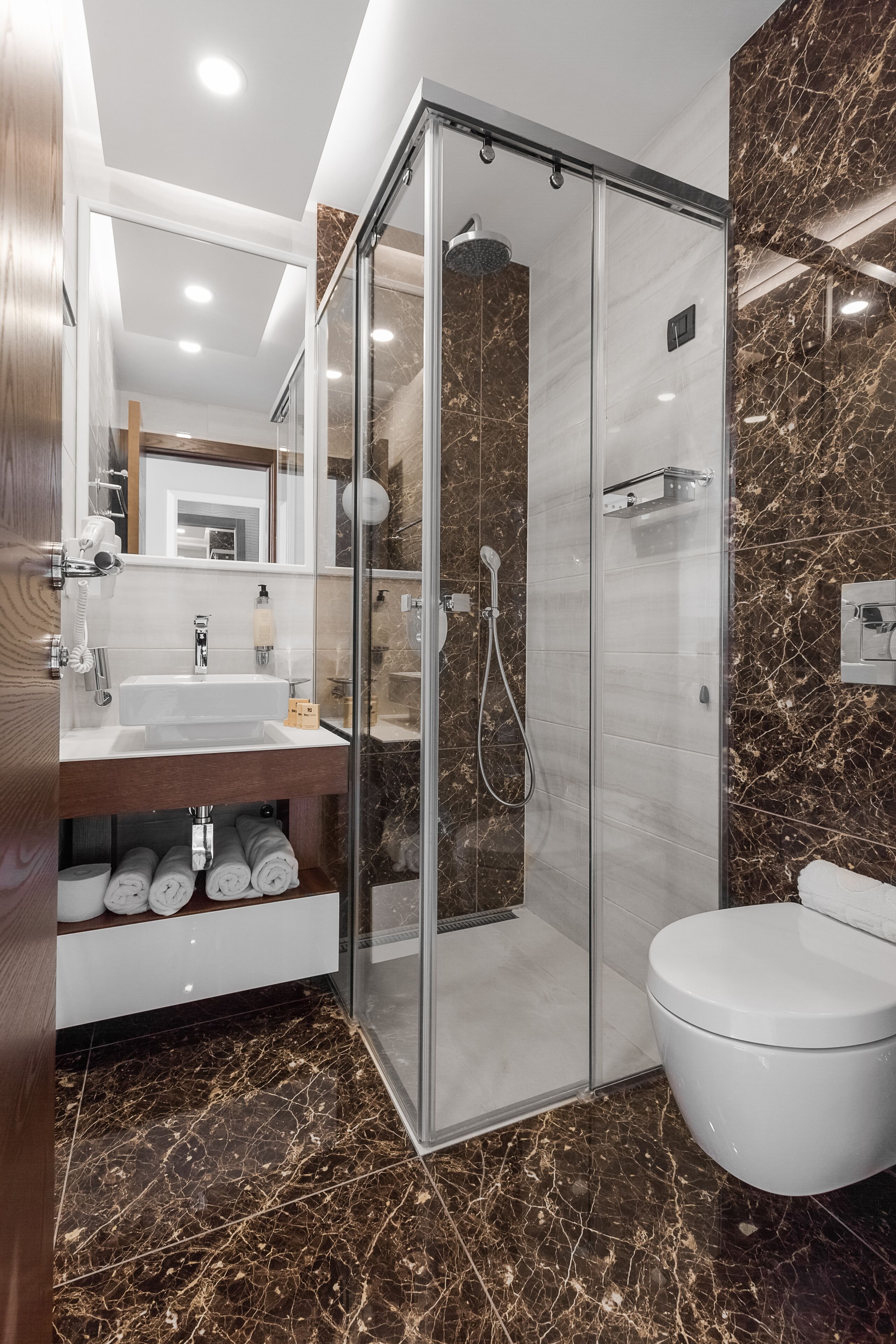 A modern bathroom with a glass-enclosed shower, a white sink, and a toilet.