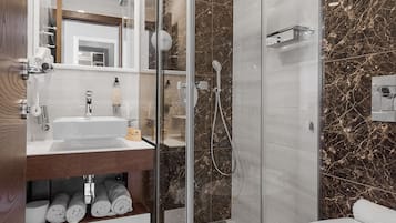Un baño moderno con ducha de vidrio, lavamanos blanco y retrete.
