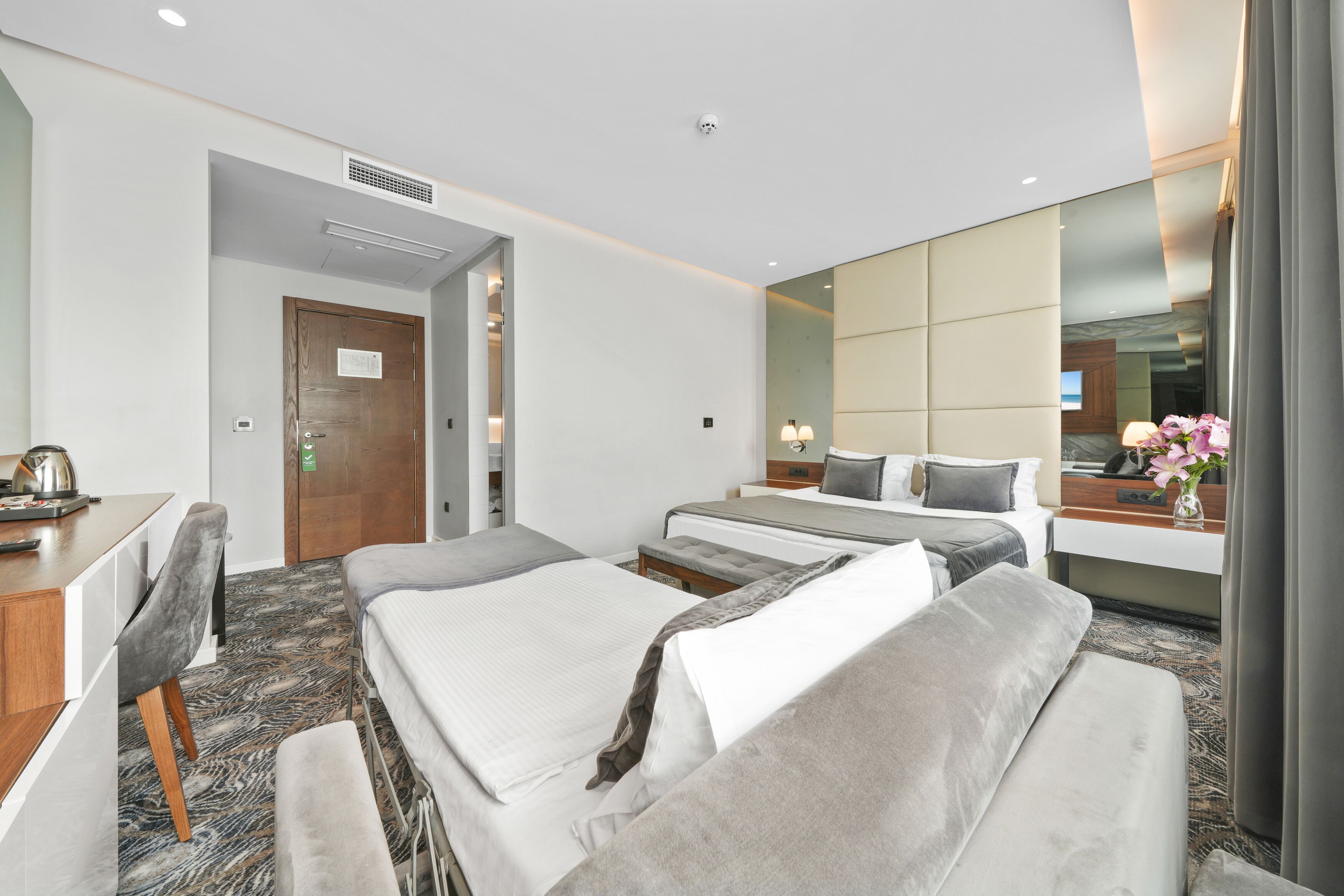 A hotel room with two beds, a desk, and a large mirror.
