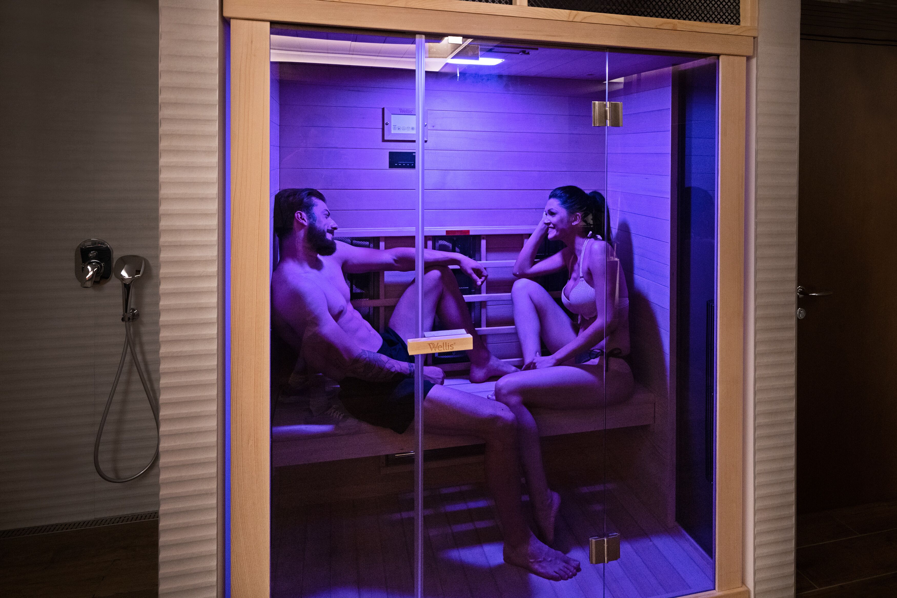 A sauna with a glass enclosure, wooden benches, and a control panel.