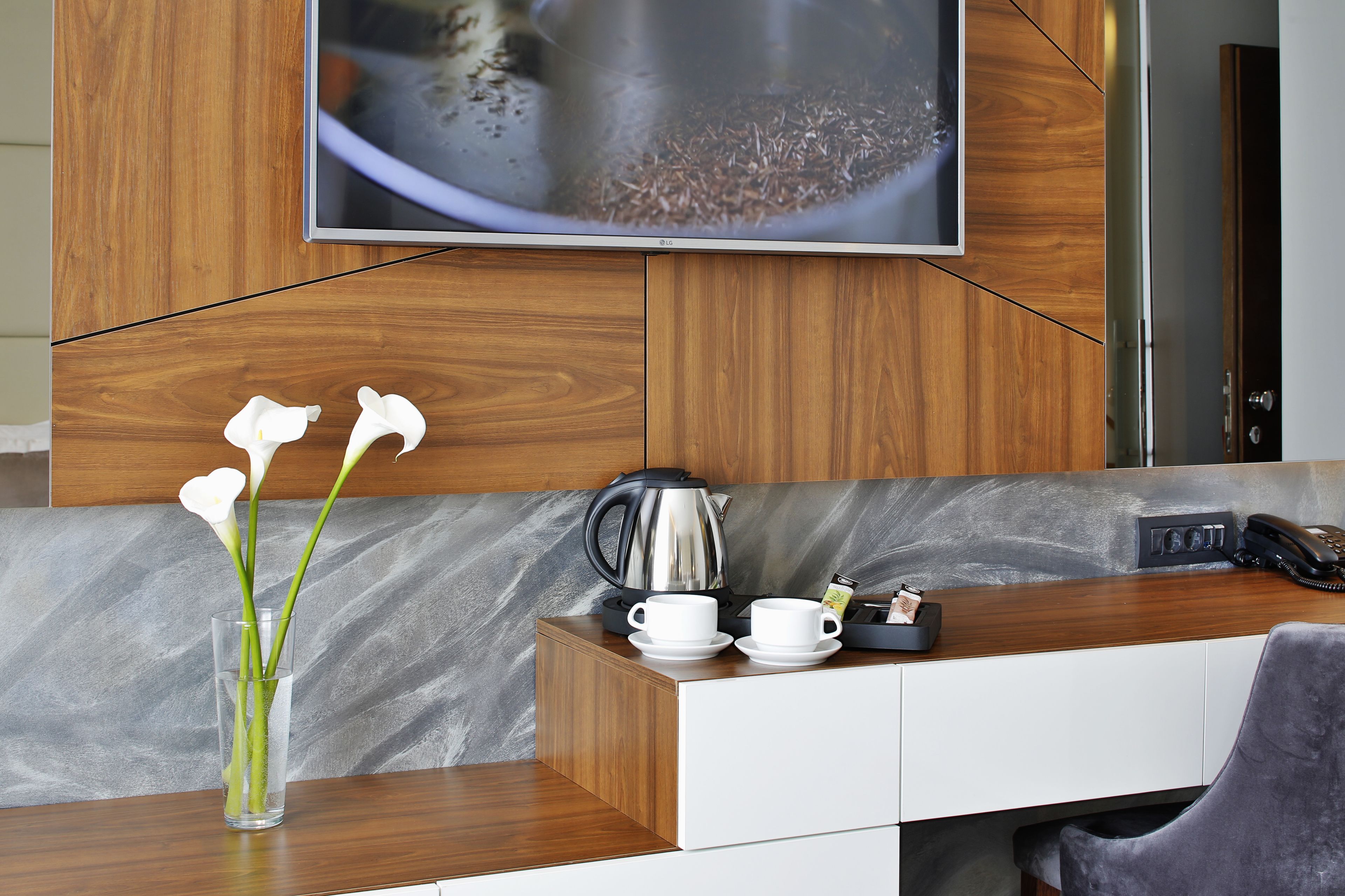 Una cocina moderna con encimera de madera, una cafetera, dos tazas blancas y un florero con flores blancas.