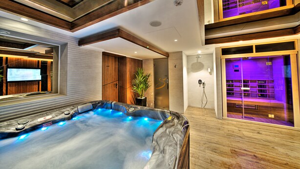 A modern spa area with a hot tub, wooden flooring, and a television screen. - Sky hotel (Belgrade)