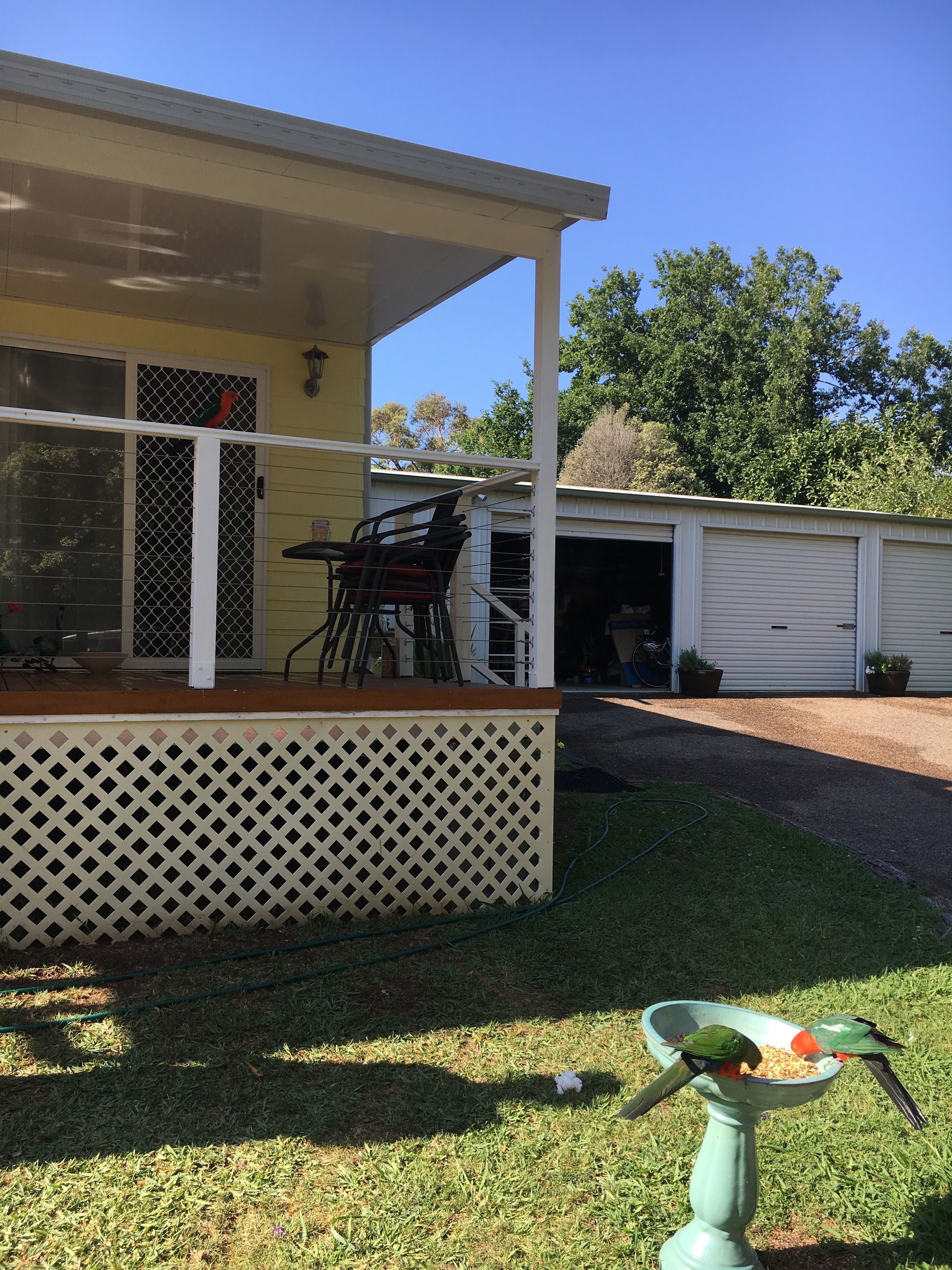 A house with a covered porch, a garage, and a bird feeder on the lawn.