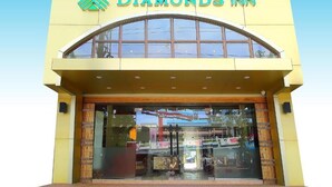 Exterior del Diamonds Inn, con fachada amarilla, grandes ventanales arqueados y un logotipo destacado sobre la entrada.
