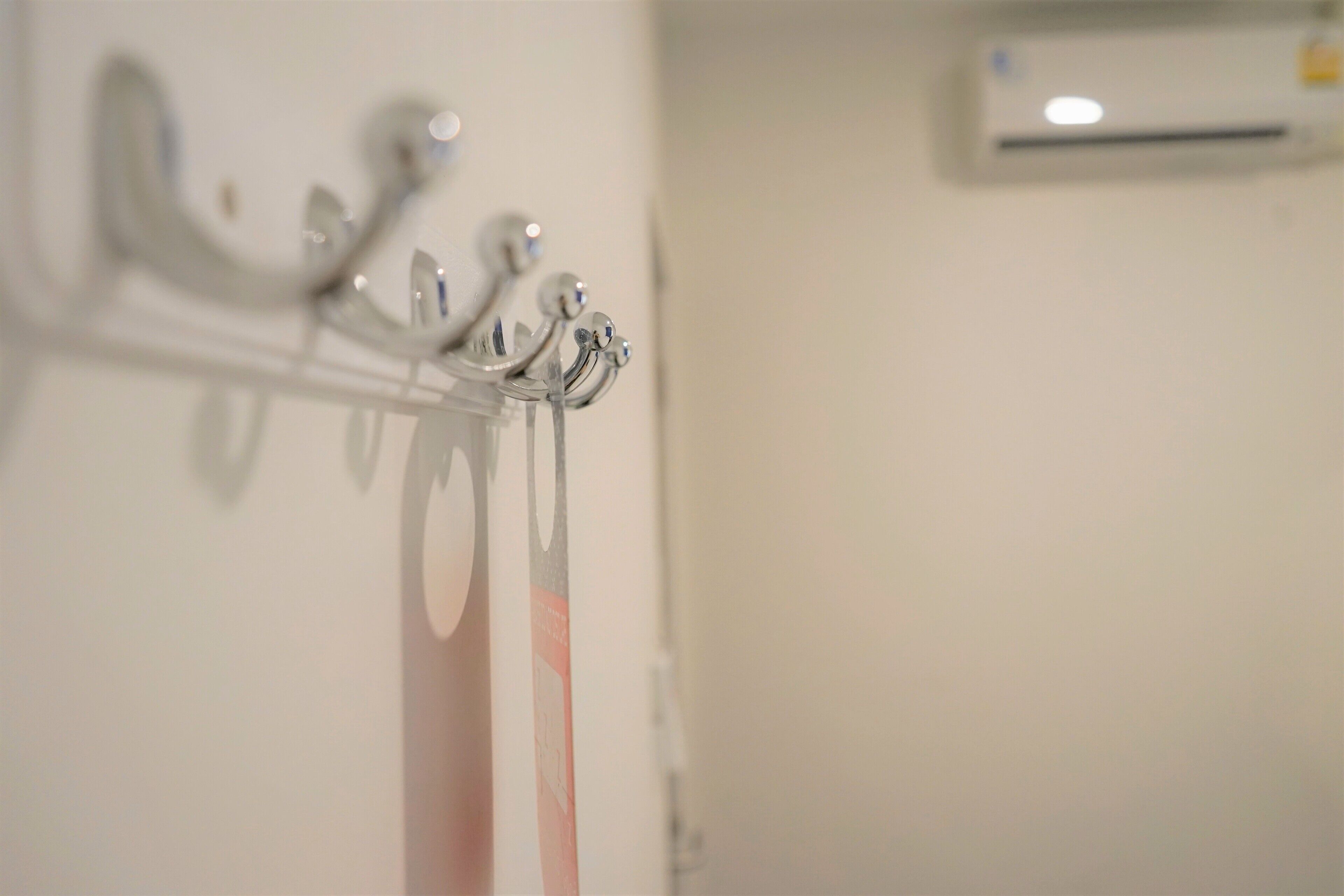 A close-up of a metal coat rack with hooks, a towel, and a wall-mounted air conditioner.