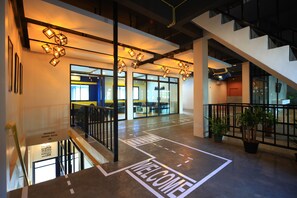 A modern interior with a 'WELCOME' sign on the floor, a staircase, and a view into a dining area. - Tuk Tuk Hostel (Bangkok)