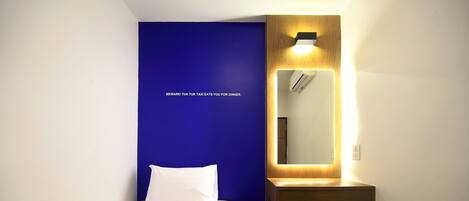Une chambre d’hôtel avec un lit, un bureau, un miroir et une chaise jaune.