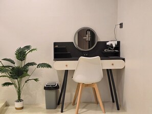 A modern workspace with a desk, chair, mirror, and potted plant. - Tuk Tuk Hostel (Bangkok)