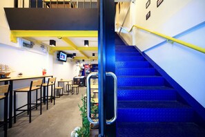 A modern interior with a staircase, seating area, and a counter. - Tuk Tuk Hostel (Bangkok)
