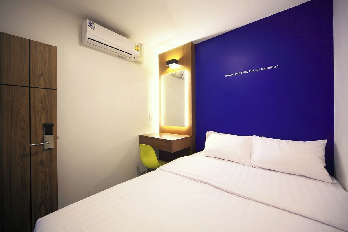 Une chambre d’hôtel équipée d’un lit, d’une table de chevet, d’un miroir, d’un appareil de climatisation et d’une armoire.