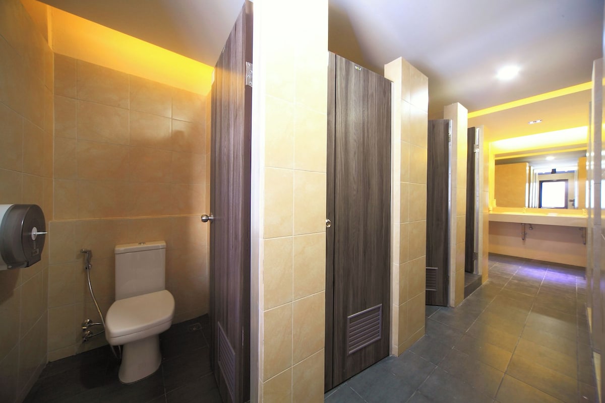 A modern bathroom with a toilet, a paper towel dispenser, and a wooden door.