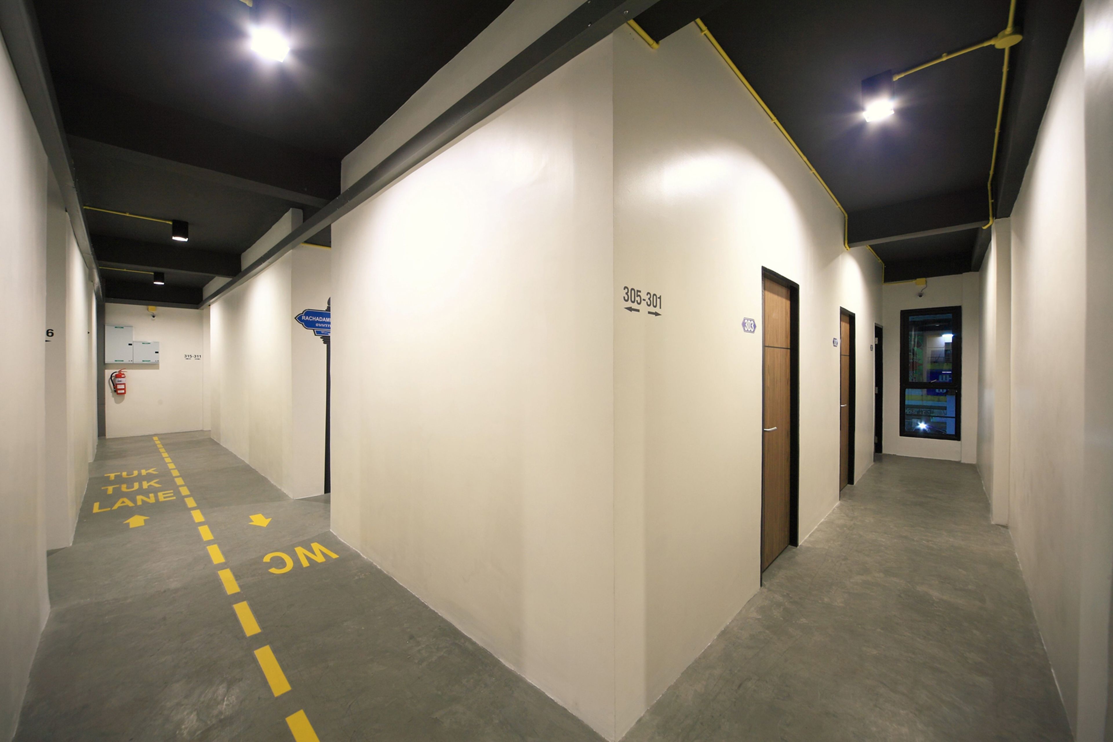 A hallway with directional arrows on the floor, a fire extinguisher, and a digital display on the wall.