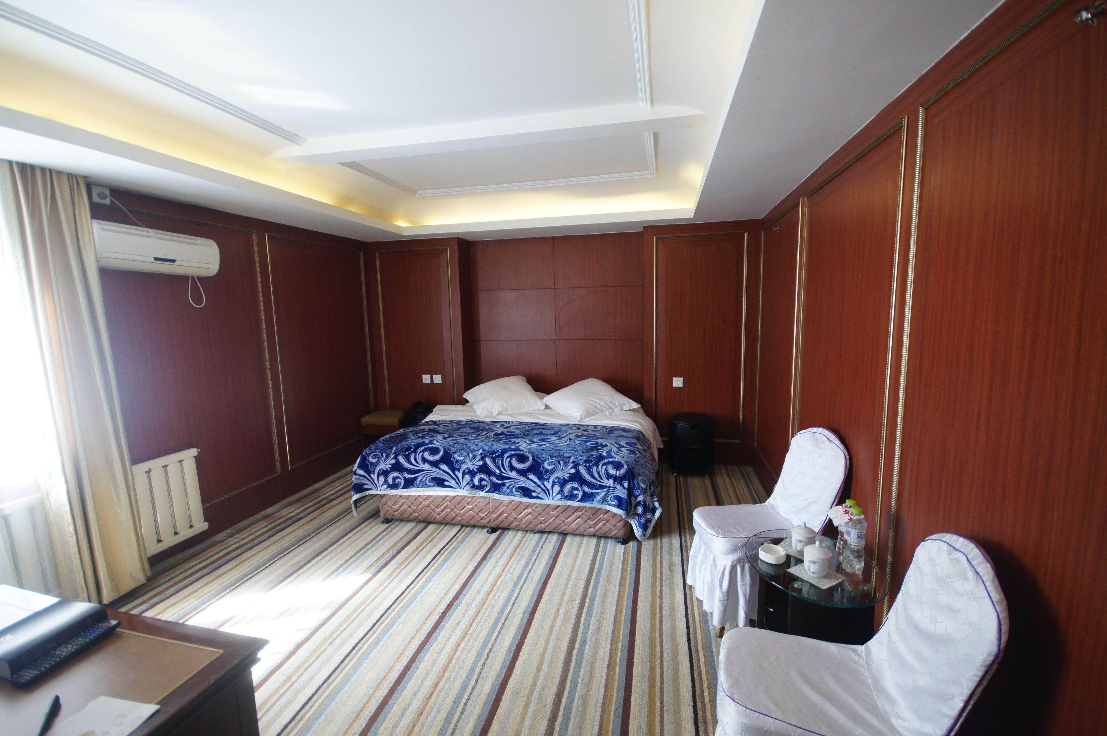 A hotel room with a bed, bedside table, and a small table with chairs.