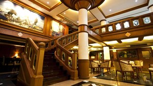 A grand lobby with a central staircase, ornate columns, and a large mural depicting a historical scene. - Zaza Hotel (Samut Prakan)