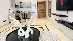 A modern kitchen with a dining area, a TV mounted on the wall, and a wooden door. - La Perle de Gauthier  by StayInMorocco (Casablanca)