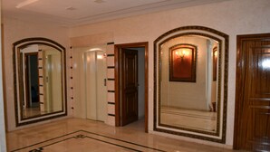 A hallway with mirrored walls, a patterned floor, and a wooden door. - La Perle de Gauthier  by StayInMorocco (Casablanca)
