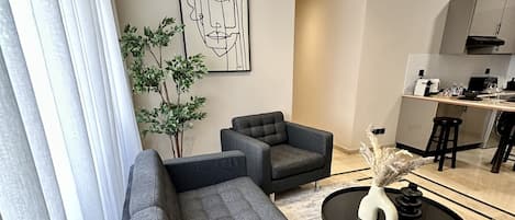 Een moderne woonkamer met een grijze modulaire bank, een ronde salontafel en een minimalistische inrichting.
