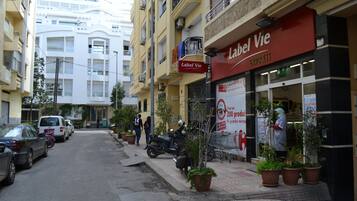 Une rue bordée de voitures garées et un bâtiment sur lequel on peut lire l’inscription « Label Vie Express ».