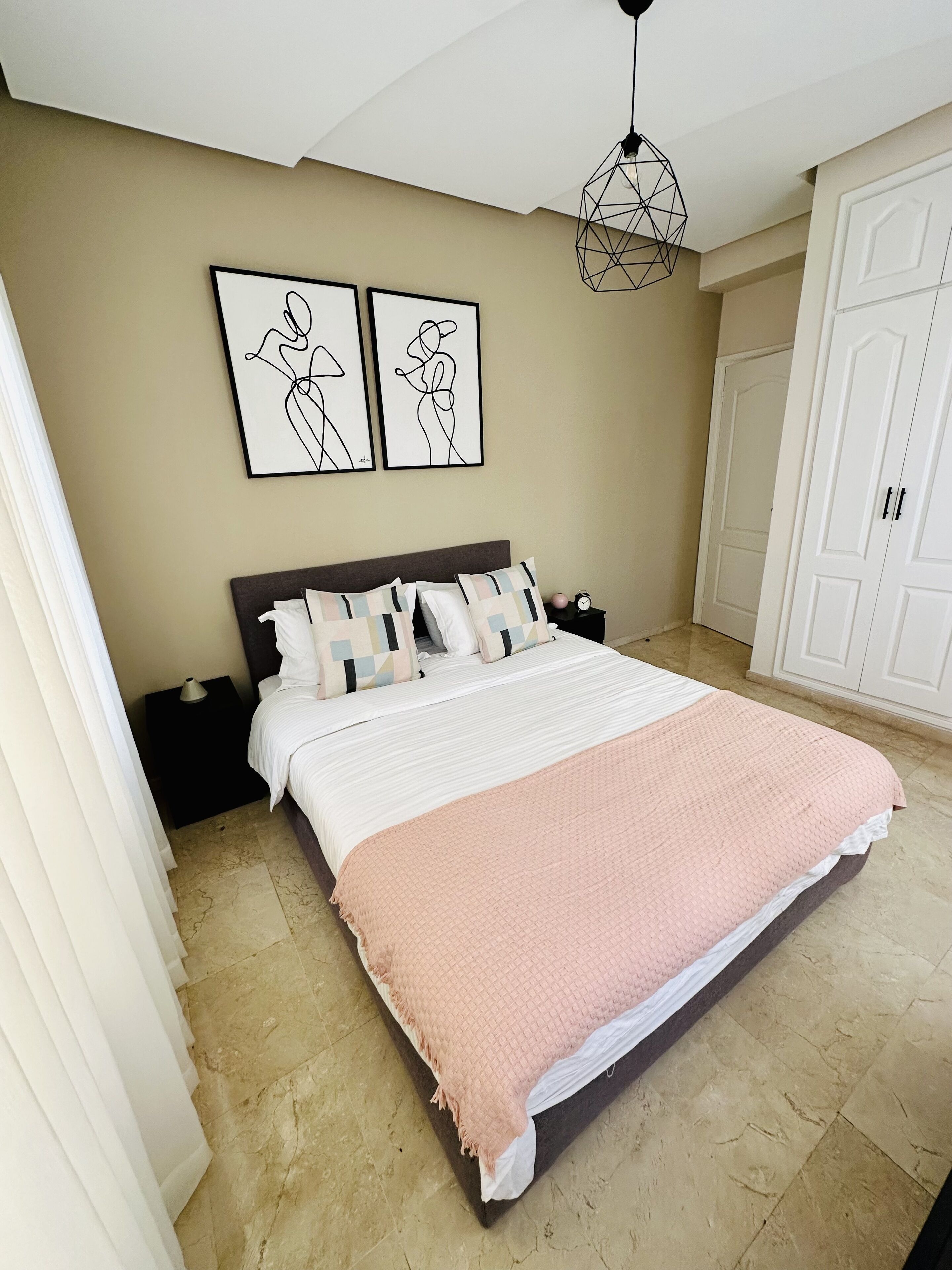A bedroom with a large bed, a nightstand, a dresser, and a wardrobe.