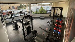 A gym with various exercise equipment, large windows, and a view of the city. - HD Plaza Hotel (Assis)