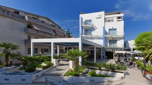 A modern hotel with a covered outdoor area, multiple balconies, and a variety of plants. - Hotel Antares (Alba Adriatica)