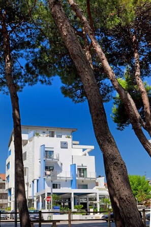 Un edificio moderno con fachada blanca, varios balcones y un cielo azul despejado.