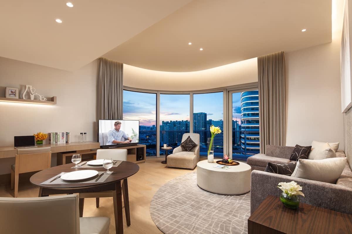 A modern living room with a dining area, a television, and a large window with a city view.
