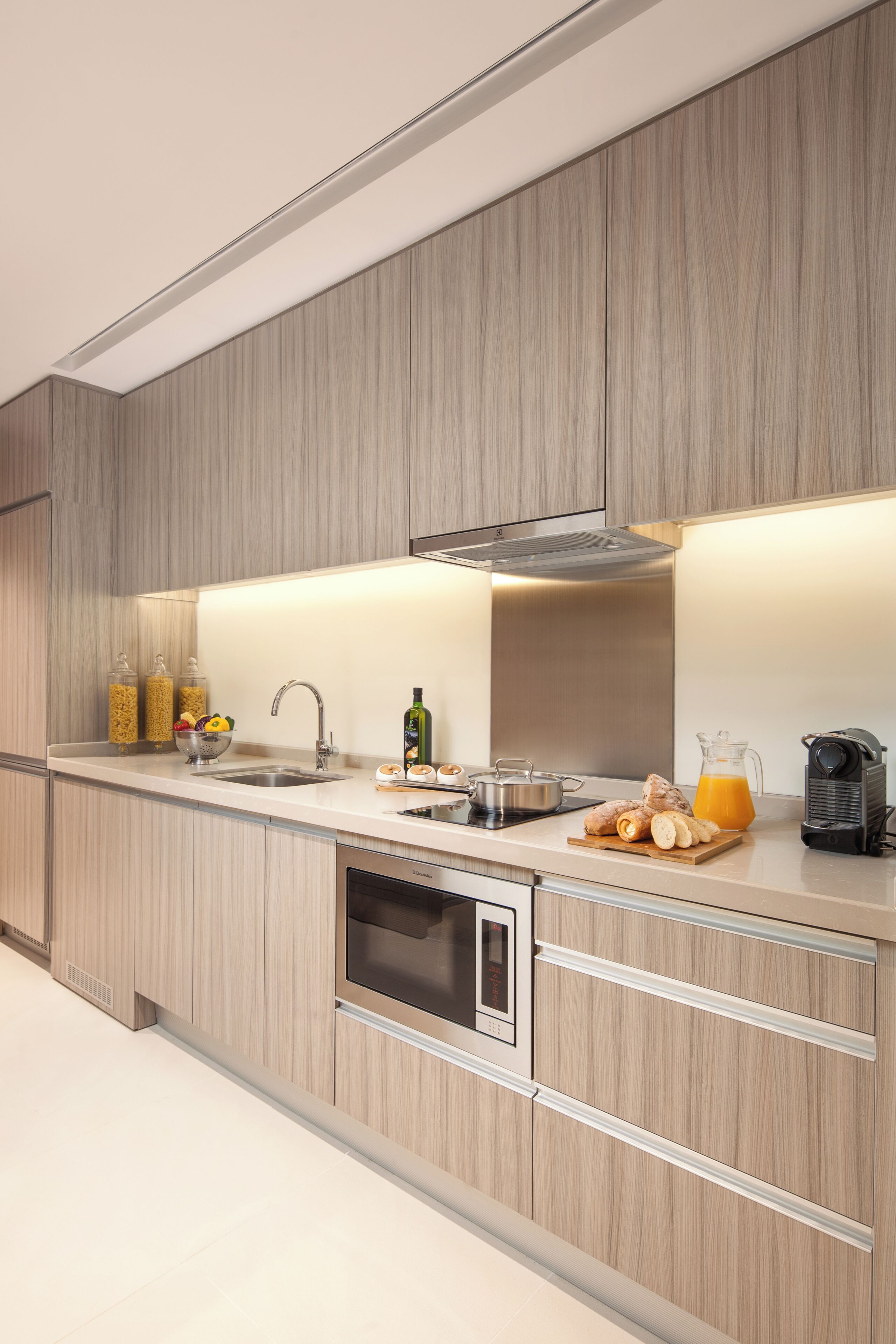 A modern kitchen with a stainless steel sink, a built-in oven, and a coffee maker on the counter.